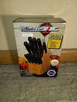 Box front showing the Master Cut 16-piece cutter set in hardwood block with utensils visible inside the block, including multiple knives with black handles.
