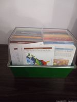 Top view of the green plastic box container holding the plant and gardening cards, showing some card titles like Plants and Temperature, Planning Perennial Beds.