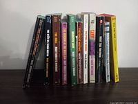 Side view showing spines of vintage paperback pulp fiction and mystery books stacked upright.