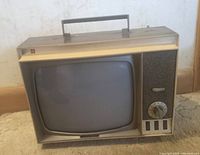 Front view of vintage portable small TV showing CRT screen, tuning dial, control buttons, and speaker grille.