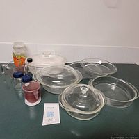 Full view of glass bakeware assortment including covered baking dishes, glass pie plates, measuring cup, vintage glass jars and pitcher.