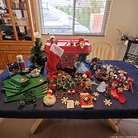 Wide shot of the whole lot on table including tree, stocking, placemats, napkins, ornaments, tins, and dog sweater