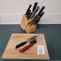Knife block holding various knives and wooden cutting board with two knives placed on top