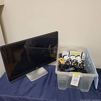 Acer 24 inch monitor next to a plastic container with various cords and devices