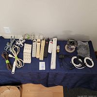 Full view of all cords, power strips, extension cords, adapters neatly laid out on table.