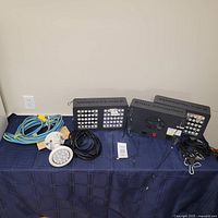 Two ViparSpectra 300W LED grow lights, single round LED light, multiple power cords and hanging hardware, and safety glasses laid on a table.