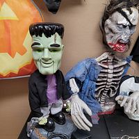 Close-up photo of the animatronic Frankenstein figure and a skeletal torso prop with tattered clothing.