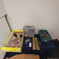 Overview photo of the entire hardware lot showing multiple boxes and bins with various hardware items including door pulls and fasteners
