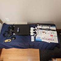 Overview of the security system items on a table including recorder, cables, mouse, remote control, and printed guides.