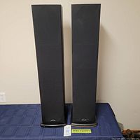 Front view of two tower speakers with grills on.