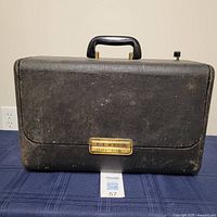 Closed black leatherette carrying case with brass Zenith Trans-Oceanic nameplate and top handle