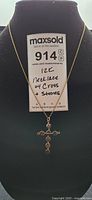 Front view of 12k gold necklace with cross pendant and stones on display stand.