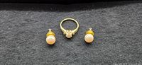Set of 14k gold pearl ring and matching pearl earrings on black background