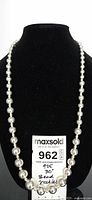 Full view of silver bead necklace on black display stand with lot tag showing 925 mark and 30-inch length