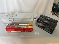 Magic Vac Champion vacuum sealer with FoodSaver roll and Magic Vac vacuum bag set on tabletop, showing all included items.