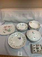 Photo showing all china pieces including plates, bowls, covered bowl, and boxed napkin rings arranged on a light background.