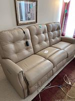 Front view of three-seat beige leather power reclining sofa showing tufted cushions and nailhead trim