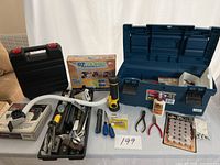 Full view of toolbox with open lid showing tools inside along with additional boxed items and separate tools laid out on table.