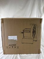 Closed original cardboard box of industrial meat slicer with printed outline image of slicer on side.