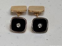Front view of cufflinks showing black enamel squares with central round diamonds and ribbed white gold borders