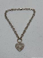 Full view of 14K white gold chain bracelet with heart charm laid flat