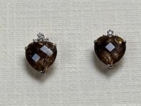 Pair of earrings front view on textured white background