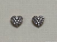 Overhead view of both heart-shaped earrings laid flat on neutral background