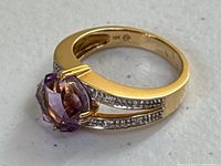 Ring laid flat showing top view of amethyst and diamond-set split shank.