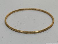 Full view of circular gold bangle on white background