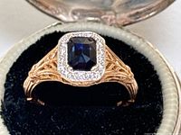 Front view of ring in open box showing sapphire and diamond halo
