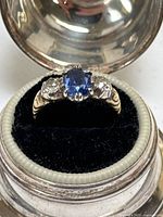 Front view of ring showing central sapphire and side diamonds in setting