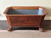 Front view showing overall shape, flame mahogany panels, interior lining, and claw feet.