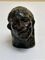 Front view of bronze head sculpture showing facial features and overall condition