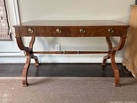 Full front view of the burl walnut desk with drawer fronts and curved supports