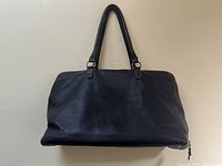 Front view of dark brown pebbled leather duffel bag with dual top handles