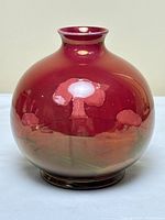 Front view of spherical vase showing ruby red lustre glaze and central tree motif