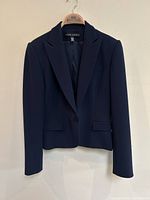 Front view of navy blazer displaying single-button closure, notched lapel, flap pockets and overall silhouette