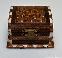 Front view showing geometric inlaid lid pattern and metal clasp