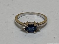 Top-down view of ring on white speckled surface showing band and stones