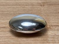 Top view of a rounded oval-shaped silver pill box showing curved smooth surface and some tarnish and dents.