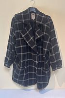 Full front view of coat hanging, showing silhouette, lapels, pockets