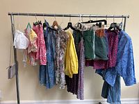 Clothing rack overview showing all items on hangers: mix of tops, dresses, skirts and shorts in assorted colors and prints