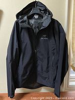 Front view of navy blue jacket on hanger showing full-zip closure and hood