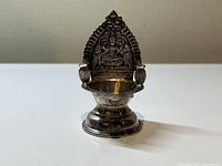 Frontal side view showing the oil bowl and detailed Lakshmi relief backplate on the Indian silver Diya lamp.