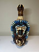 Front view of a handmade Aztec eagle warrior tequila bottle decanter with colorful stone headdress and facial details