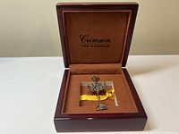 Open Crimson Fine Diamonds wooden jewelry box showing velvet interior with yellow ribbon holding the pendant