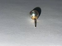 Close-up photo of single pearl stud earring showing white pearl and yellow gold post.