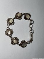 Photo of vintage sterling silver bracelet showing six oval natural moonstones each set in silver beadwork with hook clasp.