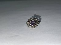 Photo of vintage sterling silver ring with central amethyst and two smaller garnet stones, showing top view and detailed band design.