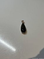 Front view of the pendant showing the teardrop-shaped glossy black onyx stone set in sterling silver.